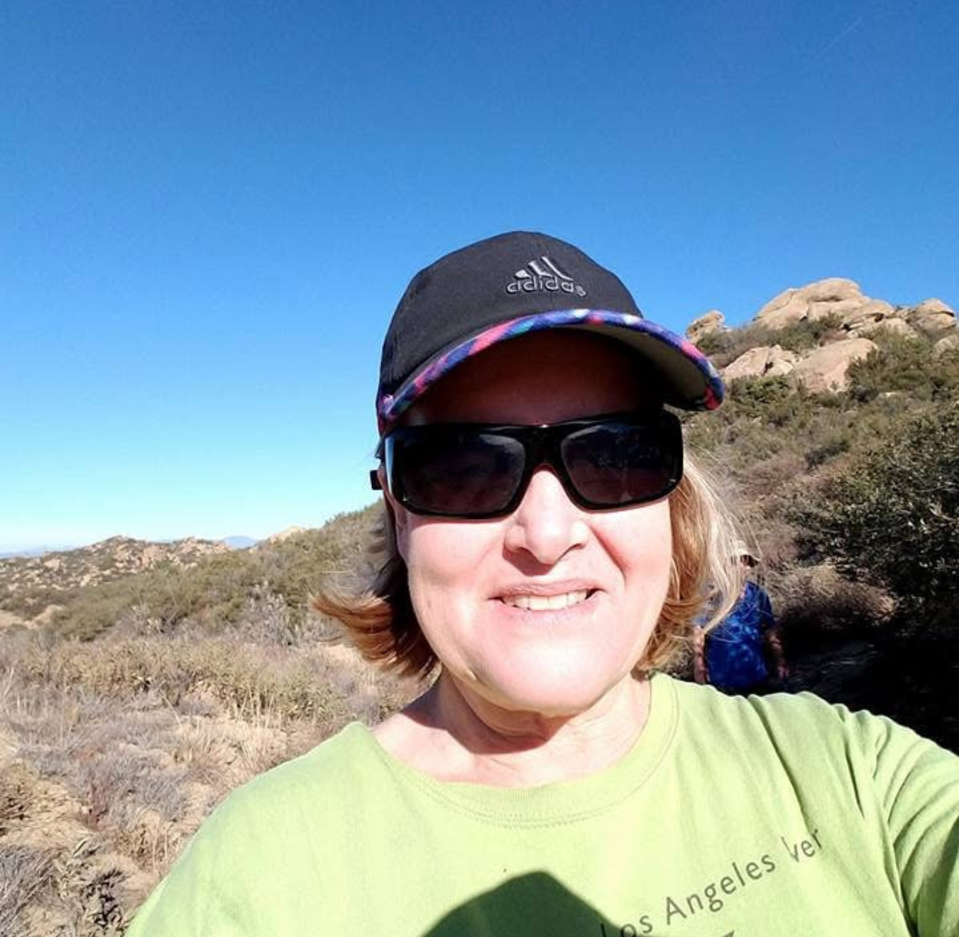 light skinned woman taking a selfie with chaparral in the background